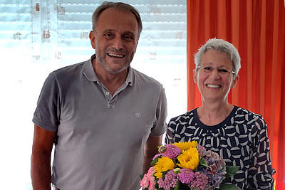 Foto des Geschäftsführers Pflege Jens Schickel, der Frau Sabine Uekermann einen Blumenstrauß überreicht